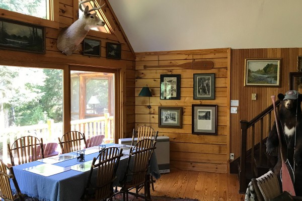 Dining area overlooking deck, view of woods and lake.