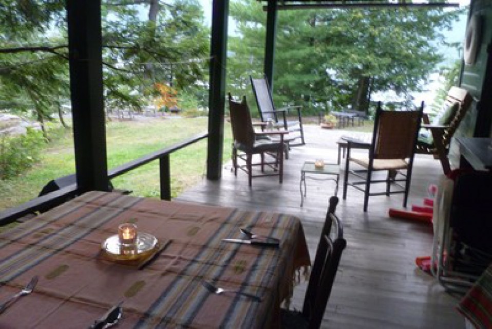 Covered porch has dining table and sitting area.