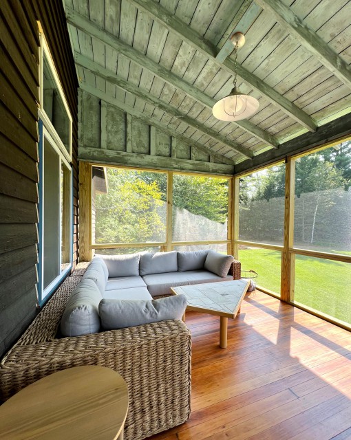 A screened in porch viewing mountains and yard.